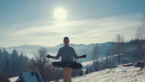 Aerial view, man practicing yoga on the background of winter mountains.