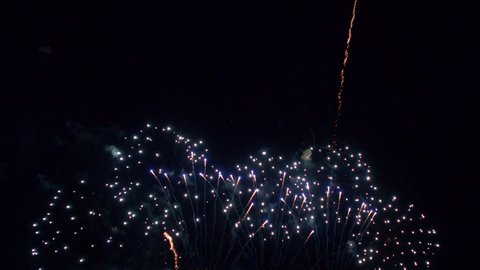 Multiple colourful firework displays exploding on a dark black sky during new year's eve.