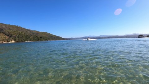 Knysna , Western Cape , South Africa - 11 14 2020: Dynamic whip pan as powerful white speed boat cruises past, sunny day