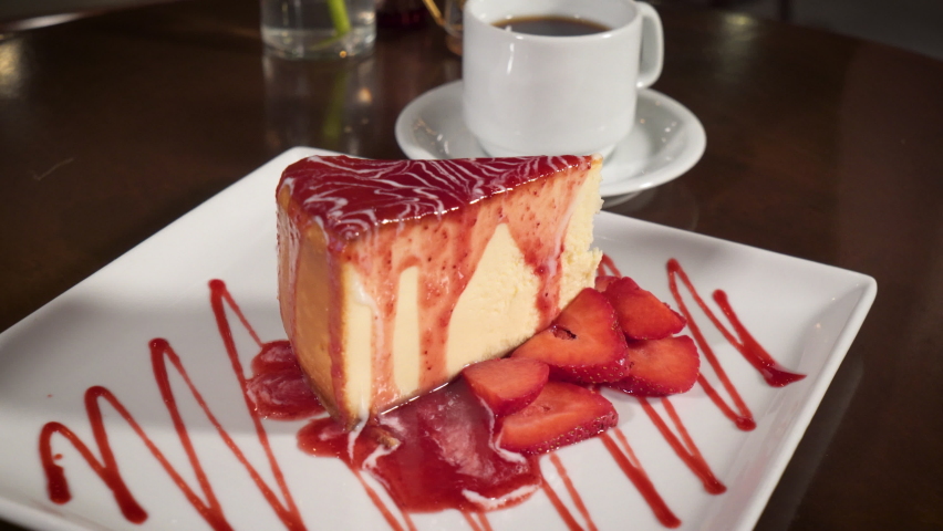 Fork digs into strawberry cheesecake, coffee and dessert fine dining, slider slow motion 4K