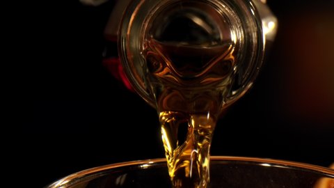 Whiskey, Brandy or cognac Pouring into Glass, on black background. Slow motion 240 FPS. Luxury Drink.