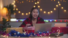 Young Asian teenage girl using laptop for video call while happy with birthday gift box