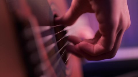 Musician plays an acoustic guitar, closeup shot. Close-up of a man's hands playing the guitar.  Male fingers fast plays on guitar. human hands plays on a guitar, soft focus