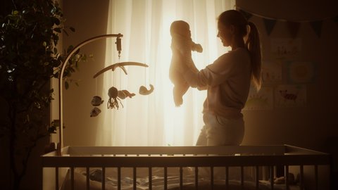 Authentic Footage of a Cute Newborn Baby Lying on the Back in Child Crib in a Cozy Warm Dark Room. Happy Mother Picks Up Neonate Toddler from the Bedroom. Concept of Childhood, New Llife, Parenthood.
