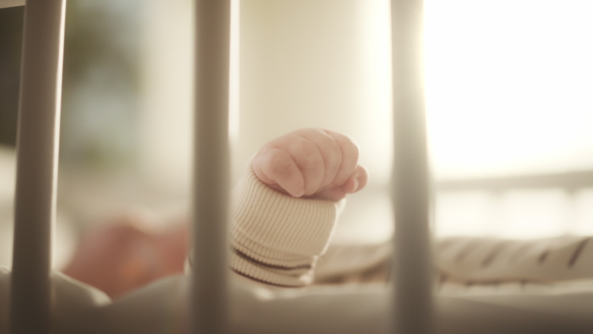 Authentic Close Up Footage of an Adorable Newborn Baby Lying on the Back in Child Crib. Tiny Human Feet of Caucasian Neonate Toddler is in Focus. Concept of Childhood, New Life and Parenthood. Royalty-Free Stock Footage #1063762924