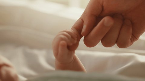 Close Up Footage of Newborn Baby Playing With Mother's Hand and Finger while Lying on the Back in Child Crib. Caucasian Neonate Toddler Bonding with Mom. Concept of Childhood, New Life and Parenthood Stock Video