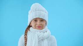 offended girl in knitted white winter outfit crying isolated on blue