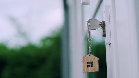 The house key for unlocking a new house is plugged into the door. The wooden keychain was moving as the wind blew. Ready-to-live house concept