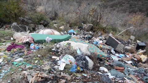 Illegal dumping. Wild garbage dump in nature. Open landfill site. Pile of garbage. Environmental pollution. Waste on landfill area. Animal offal,  plastic bottles, old furniture, car tires, packing...