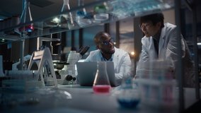 Modern Medical Research Laboratory: East Asian and Black Scientists Work on Laptop, Do Data Analysis, Talk. Advanced Scientific Pharmaceutical Lab for Medicine, Biotechnology Development. Evening Time - Powered by Shutterstock - Get 15% off with code: PIKWIZARD15