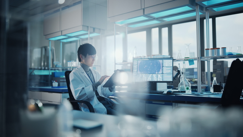 Medical Development Laboratory: Portrait of Asian Male Scientist Using Touch Screen Digital Tablet Computer, Doing Data Analysis Research. Biotechnology Specialists in Advanced Scientific Lab. - Powered by Shutterstock - Get 15% off with code: PIKWIZARD15