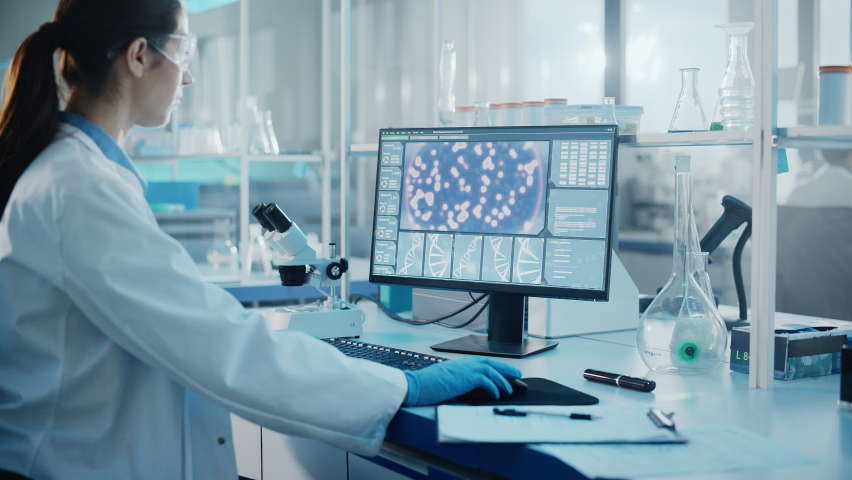 Medical Science Laboratory with Diverse Multi-Ethnic Team of Biotechnology Scientists Developing Drugs, Microbiologist Working on Computer with Display Showing Gene Editing Interface. Arc Dolly Shot Royalty-Free Stock Footage #1063773205