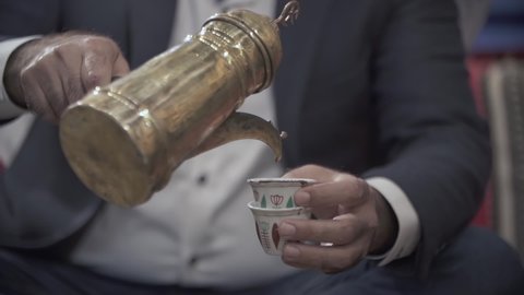 Man's hand pouring turkish arabic coffee in a cup, slow motion