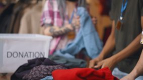 Close up of volunteers sorting donated clothes in charity shop. Team of workers unpacking boxes with clothes in second hand store. Charity and donation concept - Powered by Shutterstock - Get 15% off with code: PIKWIZARD15