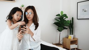 Little daughter want to sing the song she listening music with her mother on the smartphone. Asian young mother and adopted child look at smartphone together. - Powered by Shutterstock - Get 15% off with code: PIKWIZARD15