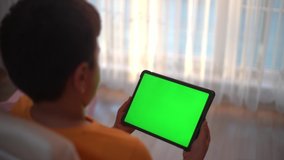 A boy playing game and watching with his tablet green screen. - Powered by Shutterstock - Get 15% off with code: PIKWIZARD15