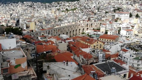 Kavala, Greece - August 13, 2020: Top view from Kavala city and Kavala aqueduct in the center of the city. Three tourists admiring the view .
