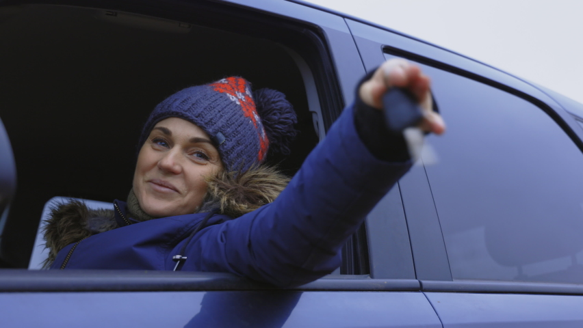 Happy woman driver holding auto keys in her car