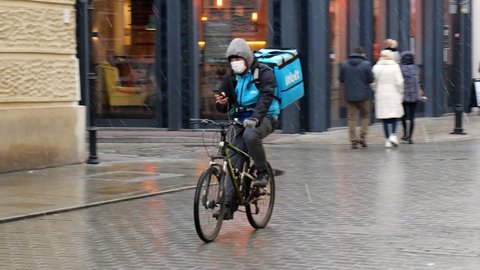 Krakow, Małopolska, Poland - November 2020: Wolt company bike driver, fast-food delivery biker passing by, going through the crowdy street. Mobile app online food ordering, food delivery platform