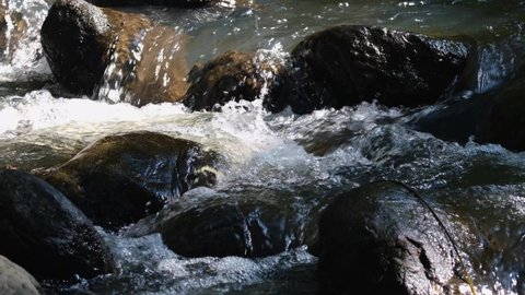 Water Flowing Through Rocks making water sounds and white water bubbles; 4K long footage perfect for adding text or narration for a wildlife docu, add ambience sound for ASMR, meditations and rest.