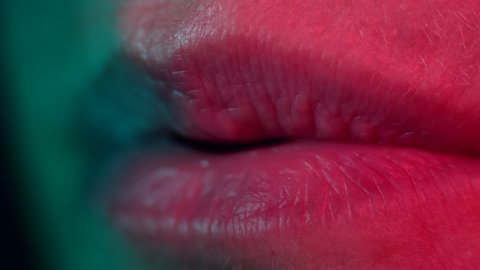 Close up of lips blowing. Colourful lighting macro shot. High quality audio. 