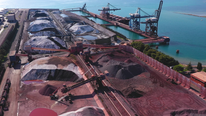 Aerial - Flyover port stocked with coal. Flying over a large industrial port. International industrial port, cranes and cargo ships