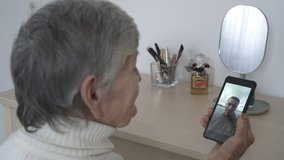 Old woman having video chat using smartphone at home chatting to grandson enjoying conversation sharing lifestyle on mobile phone.