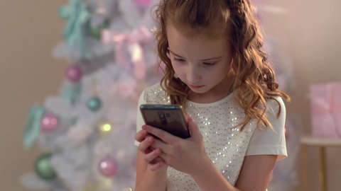 A little girl writes a letter to Santa Claus on her smartphone