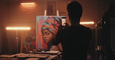 Rack focus of unrecognizable artist shooting creative portrait of black woman during work in illuminated studio