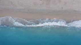 Top down view of sandy beach and turquoise sea waves at shore edge. Summer vacation travel scene