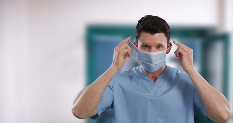 Portrait of male caucasian health worker wearing face mask in hospital. hygiene and infection prevention at hospital during coronavirus covid 19 pandemic. | Shutterstock HD Video #1063806064