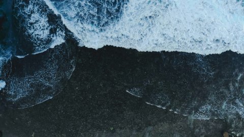 Mysterious black sand beach and foam waves. View from the top. Look like Space. Filmed on Mavic Air.