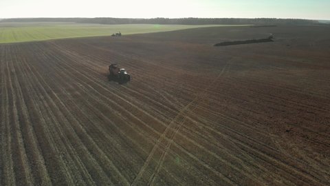 Modern tractor spreads organic fertilizers on brown fertile soil to increase productivity. Farmer with a farm machine on farmland in the fall or spring. Aerial view