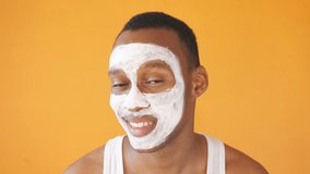 portrait of an African-American man with a cosmetic white mask on his face isolated background, he likes to take care of the skin.