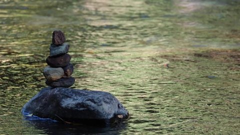 Rock Stacking seen on the left side of the frame at a jungle river in Thailand; a long footage of Rock Balancing perfect for making ASMR videos for meditation or sleeping, text can also be added.