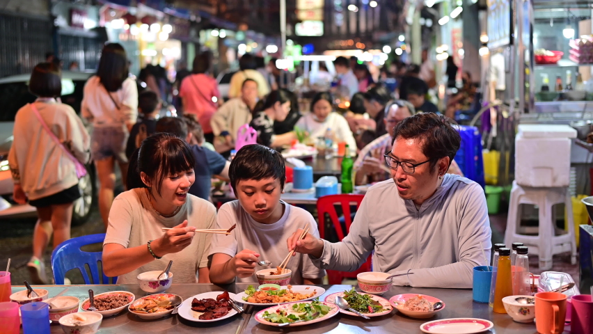 4K Asian family eating food on street food restaurant at Bangkok Chinatown with traffic | Shutterstock HD Video #1063817929