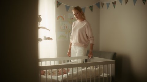 Authentic Footage of a Cute Newborn Baby Lying on the Back in Child Crib in Cozy Warm Bright Room. Happy Mother Picks Up Neonate Toddler from the Bedroom. Concept of Childhood, New Life, Parenthood.