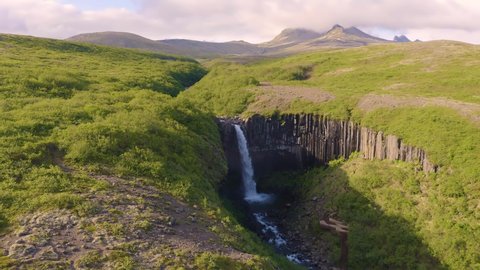Flying around the Svartifoss waterfall in Iceland. This waterfall is also known as Black Falls and it is located in Skaftafell in Vatnajokull National Park. 4K UHD video.