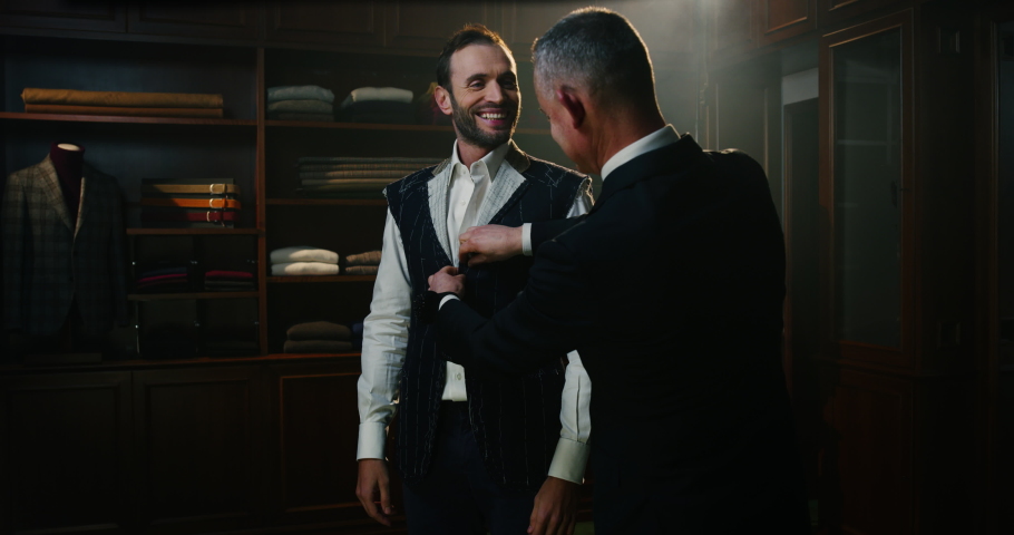 Cinematic shot of professional tailor taking measurements of client for creation custom tailored suit in a luxury tailoring atelier. Concept of fashion, handmade, hand craft, couturier and business Royalty-Free Stock Footage #1063829422