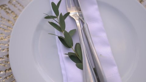 table setting at a wedding banquet decorated with an olive branch, close-up