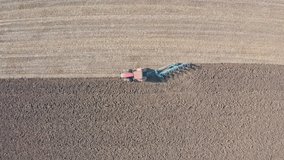 Flying and descending over field, top view. Tracking of modern tractor, drone video