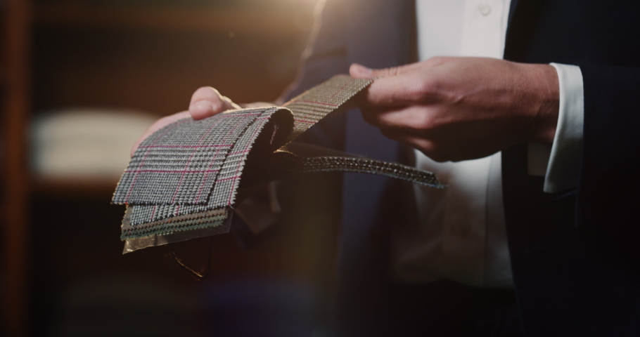 Cinematic shot of young businessman is choosing fabrics for his new custom tailored suit by designer in a luxury tailoring atelier. Concept of fashion, handmade, hand craft, couturier and business. | Shutterstock HD Video #1063832404