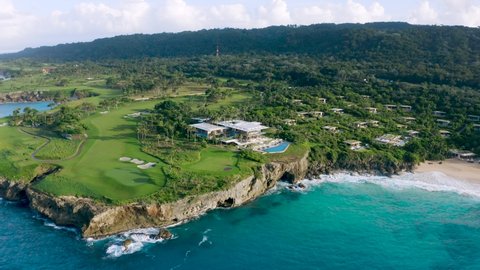 Summer travel to a paradise beach resort. Top view of a tropical resort with golf courses and villas on the mountainside. Holidays on the ocean coast Dominican Republic.