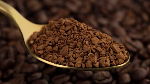instant coffee in golden spoon and coffee beans on background rotation