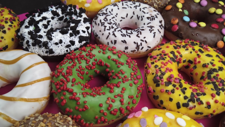 assorted donuts with icing. Background of assorted doughnuts with different flavors. The video dolly