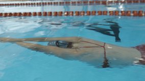 Young female swimmer training front crawl technique for swimming competition. Slow motion video.