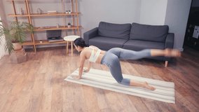 Young sportswoman working out on buttocks on fitness mat at home
