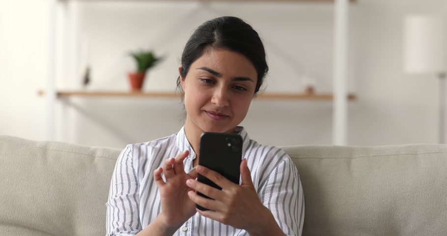 Indian woman sit on sofa hold smart phone read unpleasant sms, frustrated by received awful news feels upset. Broken device need repair, slow internet no connection to wi-fi, battery problem concept Royalty-Free Stock Footage #1063838989