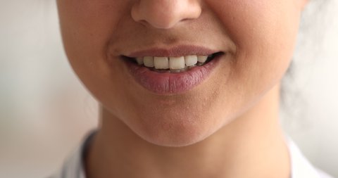 Extreme close up view face part of speaking female revealing healthy white teeth while talking, moving mouth, plump lips. Woman says text, make speech, Indian ethnicity appearance, complexion concept