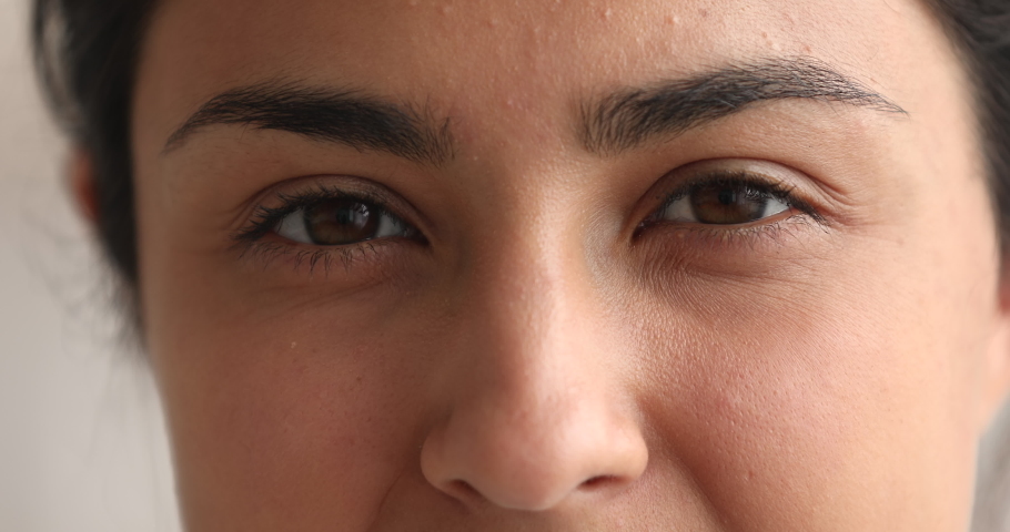 Extreme macro close up view part smiling attractive 30s Indian ethnicity woman face, happy eyes looking at camera. Positive emotions, skin care anti aging treatment, eyesight surgery, lenses concept | Shutterstock HD Video #1063839280